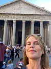 En kvinna tar en selfie framför Pantheon med turister och kolonner i bakgrunden.