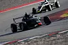 Två formelracingbilar kör snabbt genom en kurva på en racerbana.