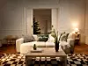 Vardagsrum med soffa, soffbord, julgran och bordslampa i ett varmt upplyst hem.