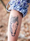 Närbild av en underarm med en tatuering föreställande ett hästhuvud.