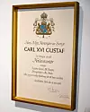 Inramat diplom eller hedersbevis med Sveriges riksvapen och texten Carl XVI Gustaf.