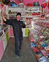 Man står i en färgglad godisbutik omgiven av hyllor med lösgodis och presentartiklar.