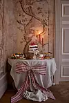 Dekorerat dessertbord med tårta, ljus och bakverk framför en väggmålning.