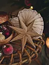Flätad korg med en guldfärgad stjärna, röda julkulor och ett pappersornament.