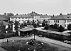 Svartvitt foto av stora institutionsbyggnader, gårdar och ett litet takförsett paviljonghus.