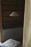 Golvlampa framför mörk trävägg med vitt draperi i förgrunden.