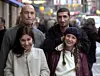Fyra personer står tillsammans på en stadsgata med folk och bilar i bakgrunden.