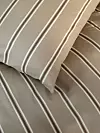Två beige- och vitrandiga kuddar på en säng med matchande överkast.
