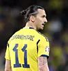 En fotbollsspelare i gul tröja med nummer 11 och uppsatt hår ses i profil.