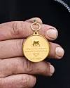 Hand som håller i LRF Mjölks guldmedalj för att ha levererat mjölk av högsta kvalitet.