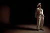 Clownen Manne står i kostym under varm spotlight på en mörk scenliknande bakgrund.