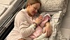 Nybliven mamma ligger i sjukhussäng och håller ett nyfött barn i famnen.