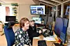 Två personer arbetar vid flera monitorer i ett kontrollrum med kamerabilder och datorutrustning.