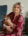 Kvinna sitter inomhus och håller en katt i famnen.