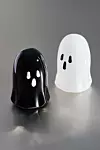 Svart och vit spökfigur av plast står på en grå yta.