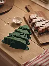 Pepparkakor på en skärbräda bredvid en grön bakform på ett träbord.