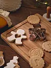 Pepparkaksformar och kakor placerade på en träskärbräda.