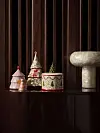Små juldekorationer och en ljus skulptur står på en mörk hylla framför en mörk trävägg.