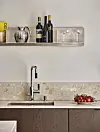 Modernt kök med hylla, vinflaskor, glas, diskho och en skål med körsbärstomater.