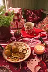 Bord med tekopp, kakfat, julklappar, ljus och dekorativa textilier i rött och rosa.