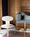 Grå soffa, bordslampa och träbord i en modern läshörna med panelväggar.