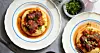 Två vita tallrikar med blå rand fotograferade uppifrån, på tallrikarna ligger polenta i botten och ragu med långkokt högrev på toppen. Intill står en liten skål med örter.